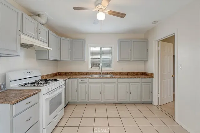 a kitchen with granite countertop a stove a sink and a refrigerator