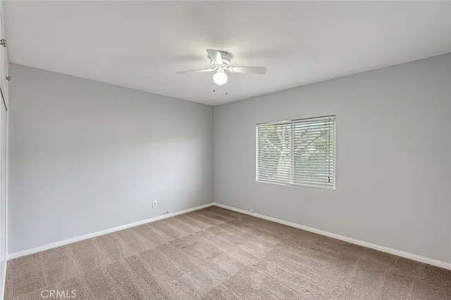 an empty room with a window and a fan