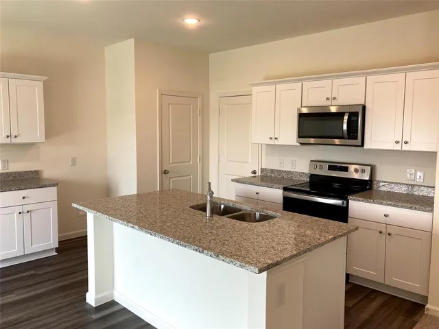 a kitchen with kitchen island wooden floors appliances and cabinets
