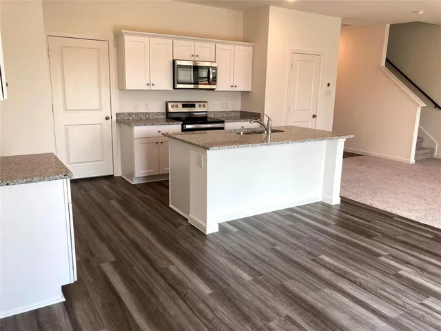 a kitchen with stainless steel appliances granite countertop a sink stove and microwave