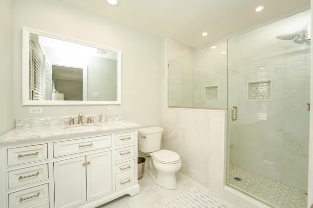 a bathroom with a toilet a sink a glass door a shower a mirror and vanity