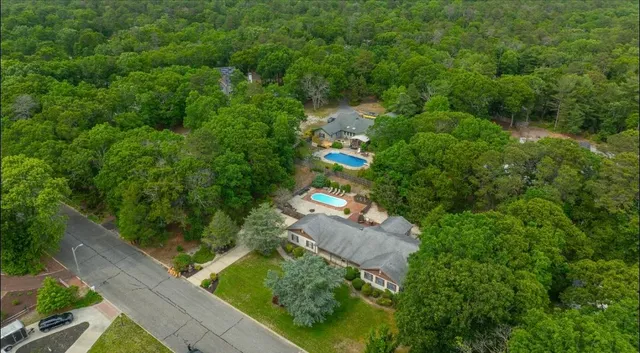 an aerial view of residential house with outdoor space and trees all around