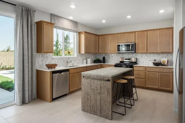 a kitchen with kitchen island granite countertop a stove a sink a refrigerator and a microwave