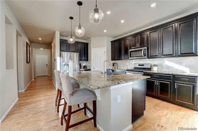 a kitchen with stainless steel appliances granite countertop wooden cabinets a stove top oven a sink and a refrigerator