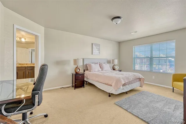 a bedroom with a bed a couch and dresser with wooden floor