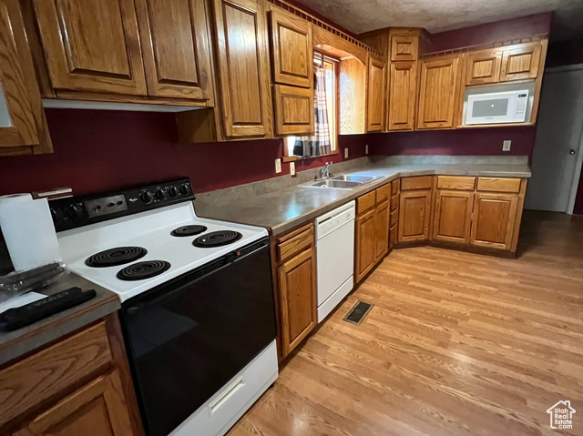 108 South Road Montpelier, ID 83254 - Photo 10 of 36 Kitchen featuring brown cabinetry, white appliances, light wood-style floors, and a textured ceiling