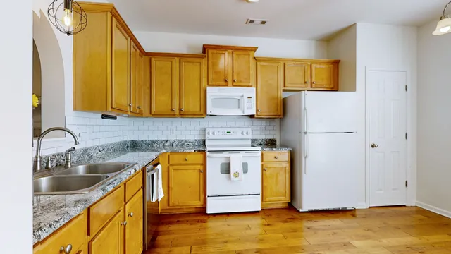 a kitchen with stainless steel appliances granite countertop a refrigerator a stove top oven a sink and dishwasher