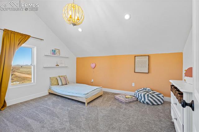 16910 Thompson Road Colorado Springs, CO 80908 - Photo 22 of 47 Carpeted bedroom featuring lofted ceiling and a chandelier