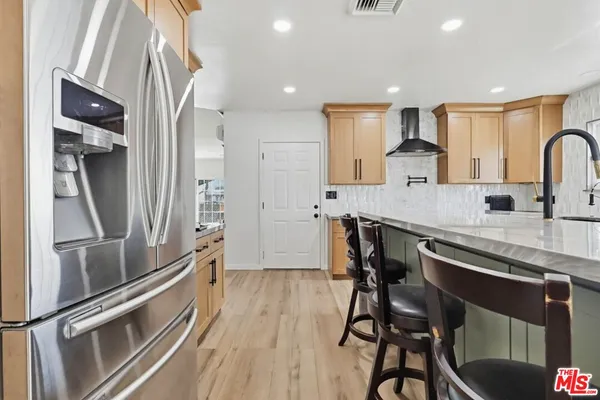 a kitchen with stainless steel appliances granite countertop a refrigerator and a stove top oven