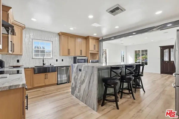 a kitchen with stainless steel appliances kitchen island granite countertop a table chairs sink and cabinets