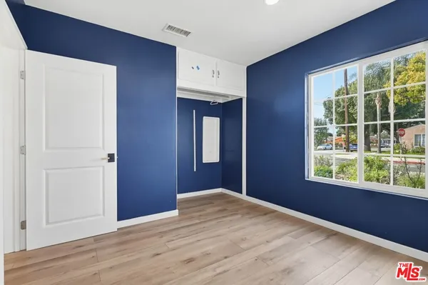 a view of an empty room with wooden floor and windows