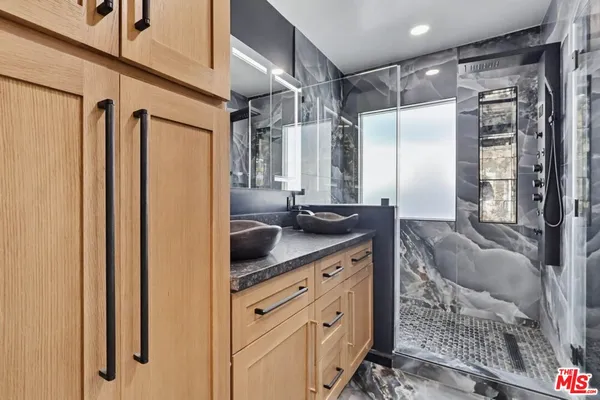 a bathroom with a granite countertop sink a mirror and shower