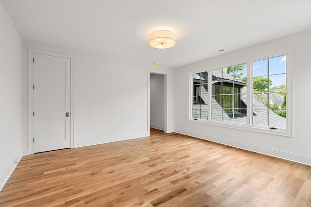 a view of an empty room with wooden floor and a ceiling fan