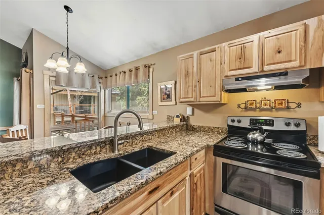 a kitchen with granite countertop a stove a sink and cabinets