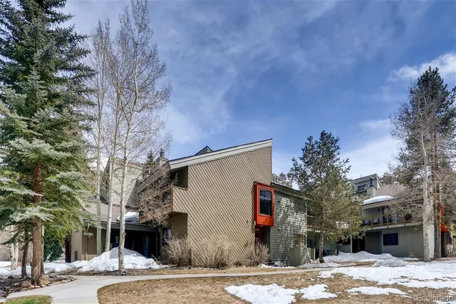 a front view of a house with a dirt yard and a large tree