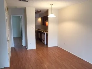 a view of kitchen and empty room with wooden floor