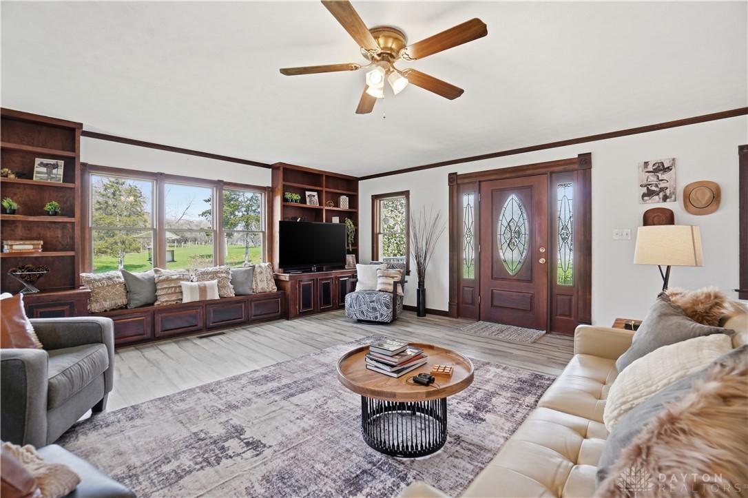 7553 Coffin Station Road Springfield, OH 45502 - Photo 29 of 95 Bright and airy living area with built-in shelving, large windows, and an elegant entry door.