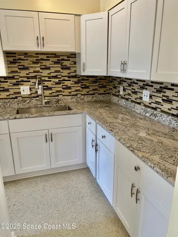 a view of kitchen with granite countertop cabinets sink and cabinets