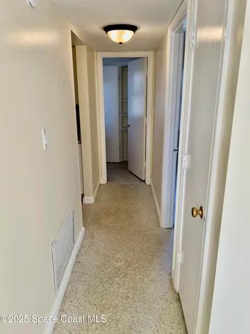 a view of a hallway with wooden floor and a bathroom