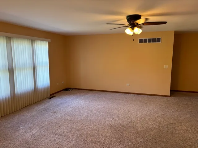 a view of an empty room with a chandelier fan