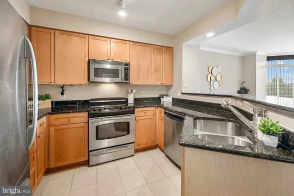 a kitchen with granite countertop a sink stainless steel appliances and cabinets