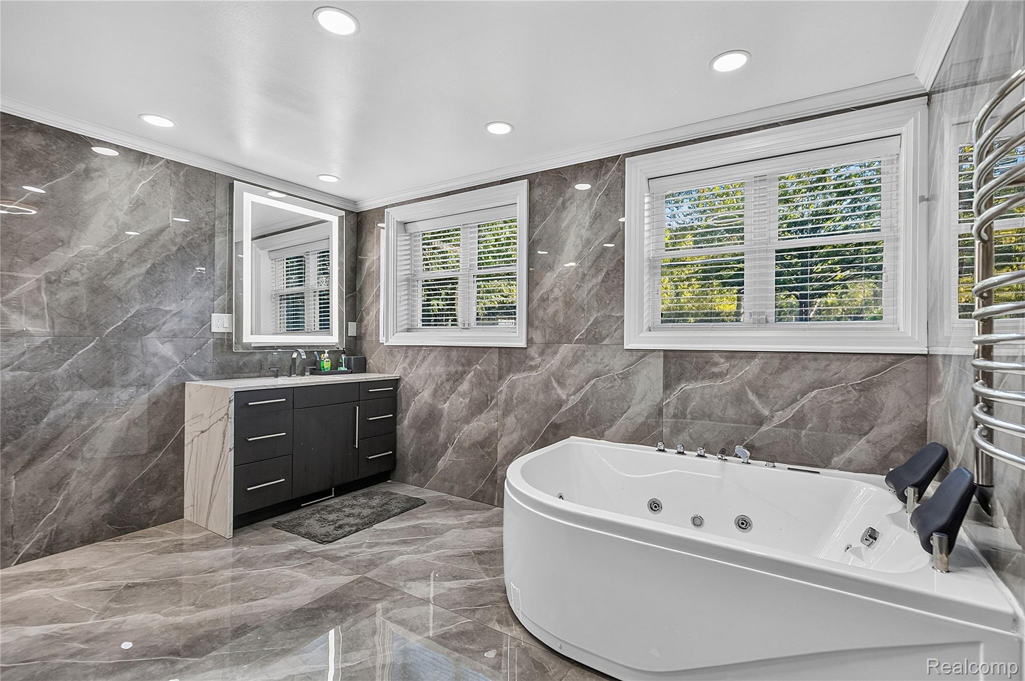 15879 Millar Road Clinton Township, MI 48036 - Photo 22 of 65 Spa-like bathroom with large format tile flooring and walls, a built-in jetted tub, recessed lighting, and a modern vanity with an illuminated mirror