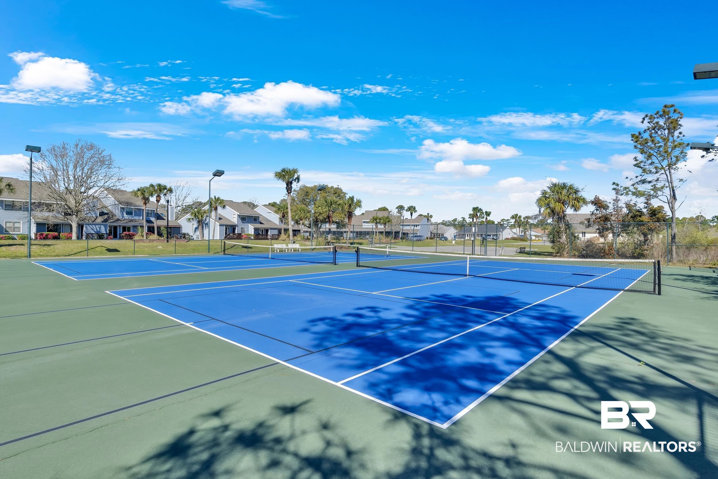 3256 Loop Road, Unit 2 Orange Beach, AL 36561 - Photo 6 of 25 Two well-maintained tennis courts with blue playing surfaces and green surrounds