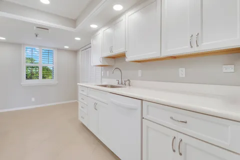 a kitchen with granite countertop white cabinets and a sink