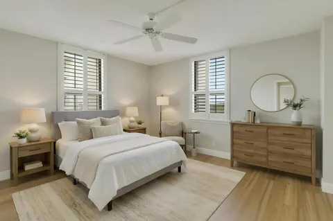 a bedroom with a bed a mirror on dresser and a window