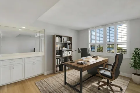 a view of a workspace with furniture and a window