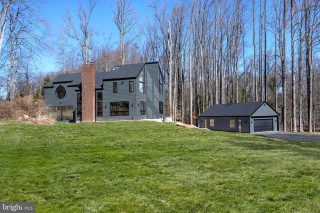 a view of a house with a big yard plants and large tree