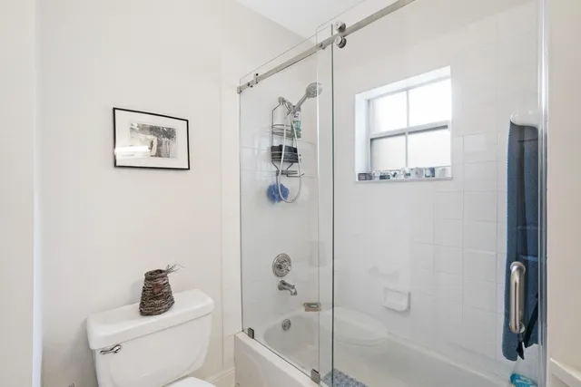 a bathroom with a shower a toilet and a window