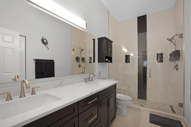 a bathroom with a double vanity sink toilet and shower