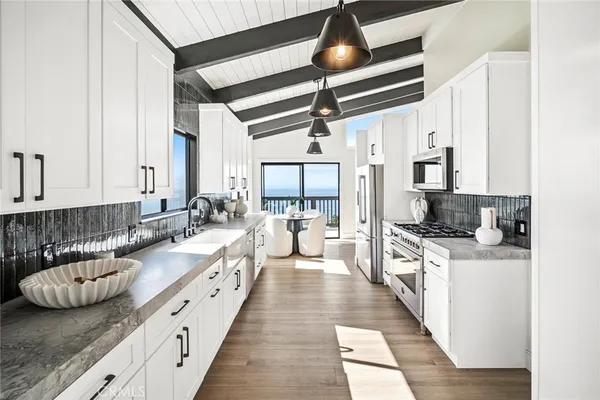 a large white kitchen with stainless steel appliances granite countertop a stove a sink and a refrigerator