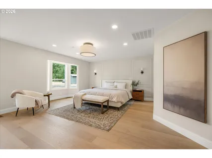 a spacious bedroom with a bed and wooden floor