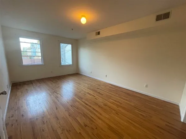 an empty room with wooden floor and windows