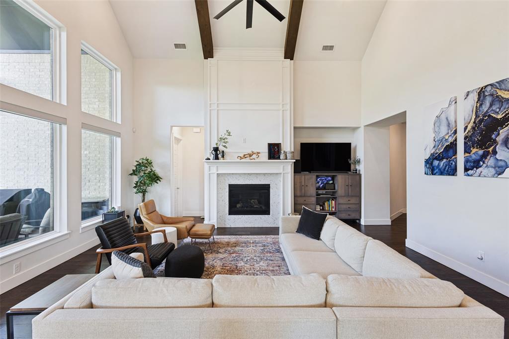15018 Crape Myrtle Road Frisco, TX 75035 - Photo 4 of 40 Vaulted ceiling with exposed wood beams, large windows, fireplace with tile surround, and dark wood-finish flooring