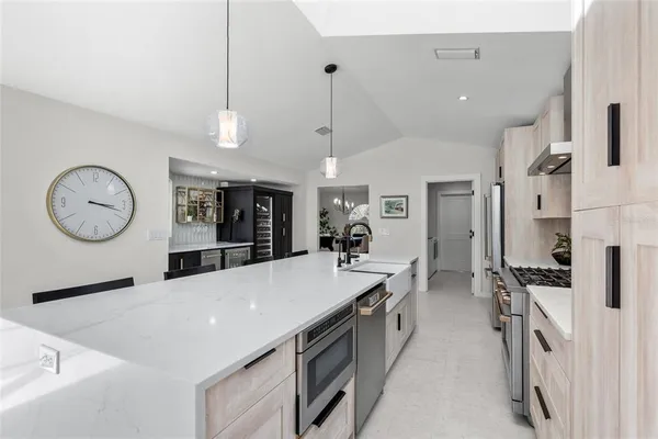 a large kitchen with stainless steel appliances a large center island attached withe living room