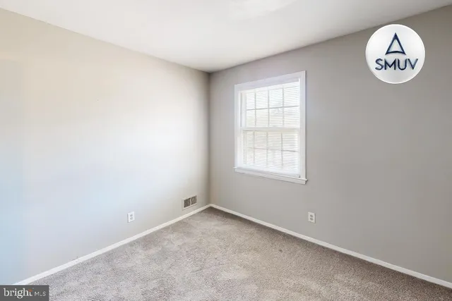 an empty room with a window and a kitchen