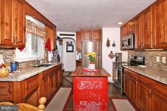 a kitchen with stainless steel appliances granite countertop a stove a sink dishwasher and cabinets with wooden floor
