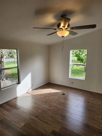 a view of wooden floor windows and chandelier fan in an empty room
