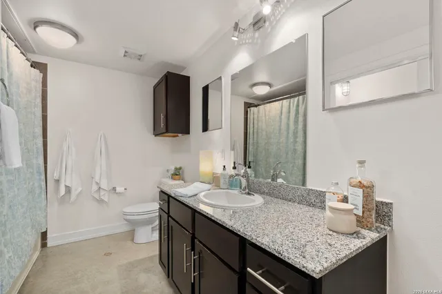a bathroom with a granite countertop sink a toilet and a mirror
