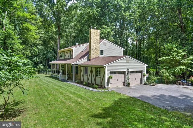 a view of a house with a yard and large trees