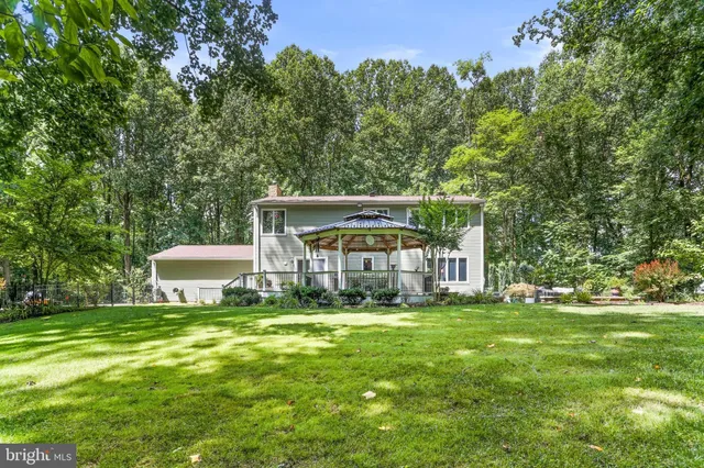 a view of a house with a big yard and large trees