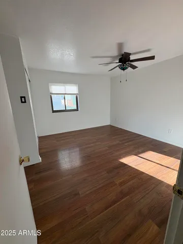 an empty room with wooden floor fan and windows