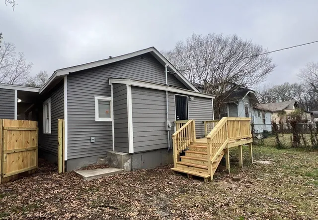 a view of a house with a yard chairs and wooden fence