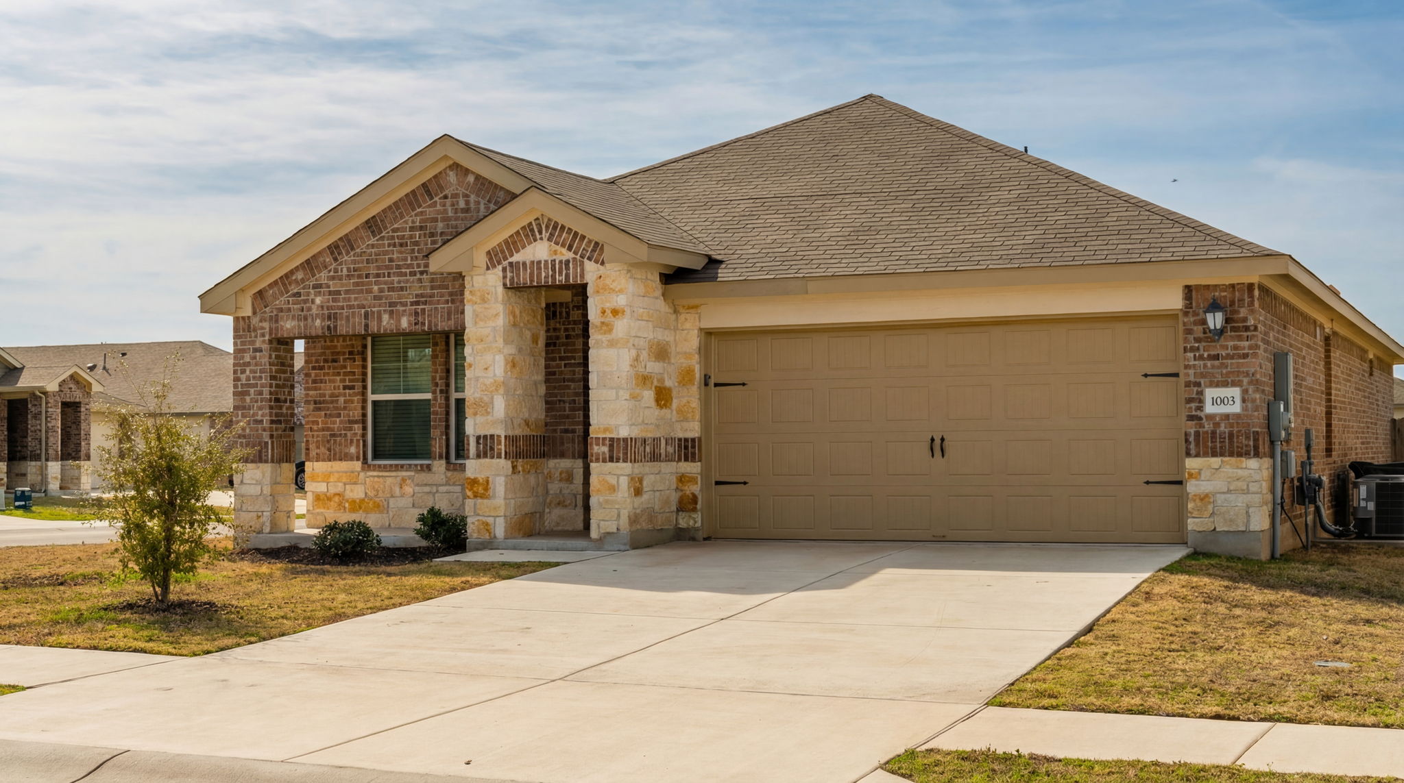 1003 Round Bale Road Hutto, TX 78634 - Photo 10 of 29 View of front of home with stone siding, brick siding, concrete driveway, and a garage