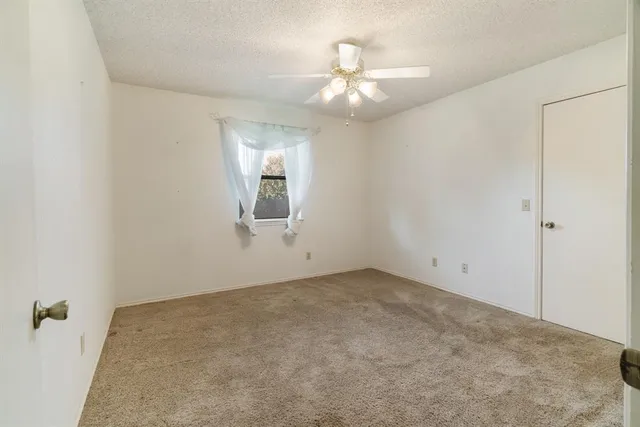 an empty room with a chandelier fan and view of bathroom