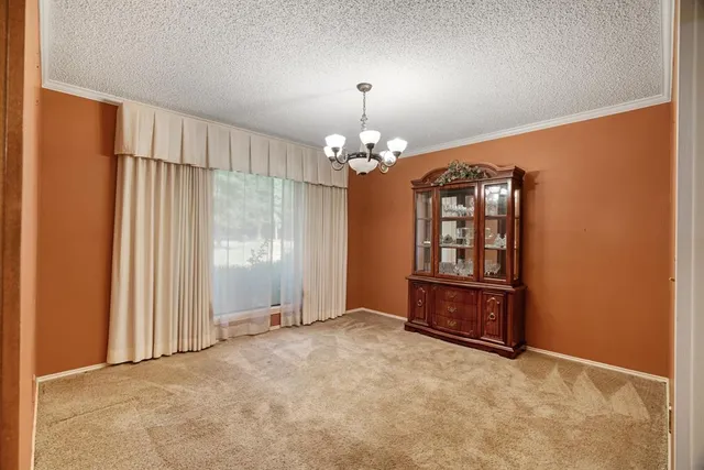 an empty room with chandelier fan and windows