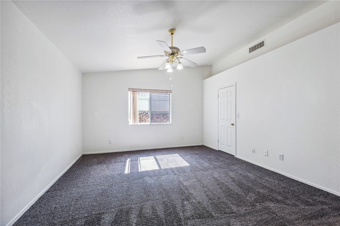 2524 South Ridge Avenue Bullhead City, AZ 86429 - Photo 28 of 64 Empty room featuring dark colored carpet, ceiling fan, lofted ceiling, and baseboards